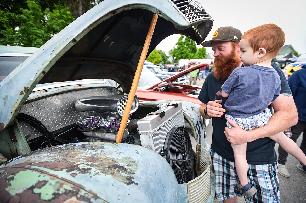 Jesse Hosler and his son Maverick Hancock look under the hood of a 1947 Austin Gasser owned by Brian Watne at The Big Shindig in Kalispell on Saturday, June 15. The Big Shindig features a wide range of classic and custom vehicles as well as live music, barbeque, beer and wine and a pin-up polar plunge. Hosted the Glacier Street Rod Association and the Desoto Grill, money raised benefits Mikayla’s Miracles and Blessings Foundation. (Casey Kreider/Daily Inter Lake)