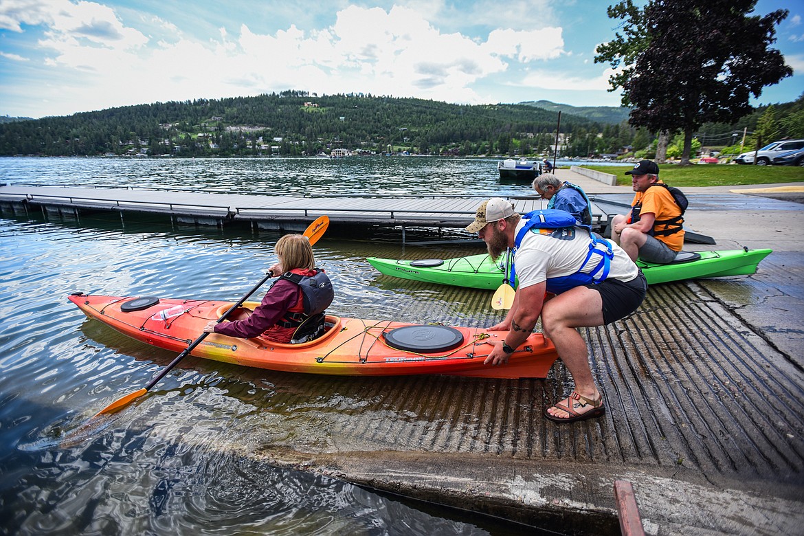 Sea Me Paddle guide Tyler Cohran and co-owner Justin Flake launch kayaks at the Somers Boat Launch during a tour on Friday, June 14. (Casey Kreider/Daily Inter Lake)