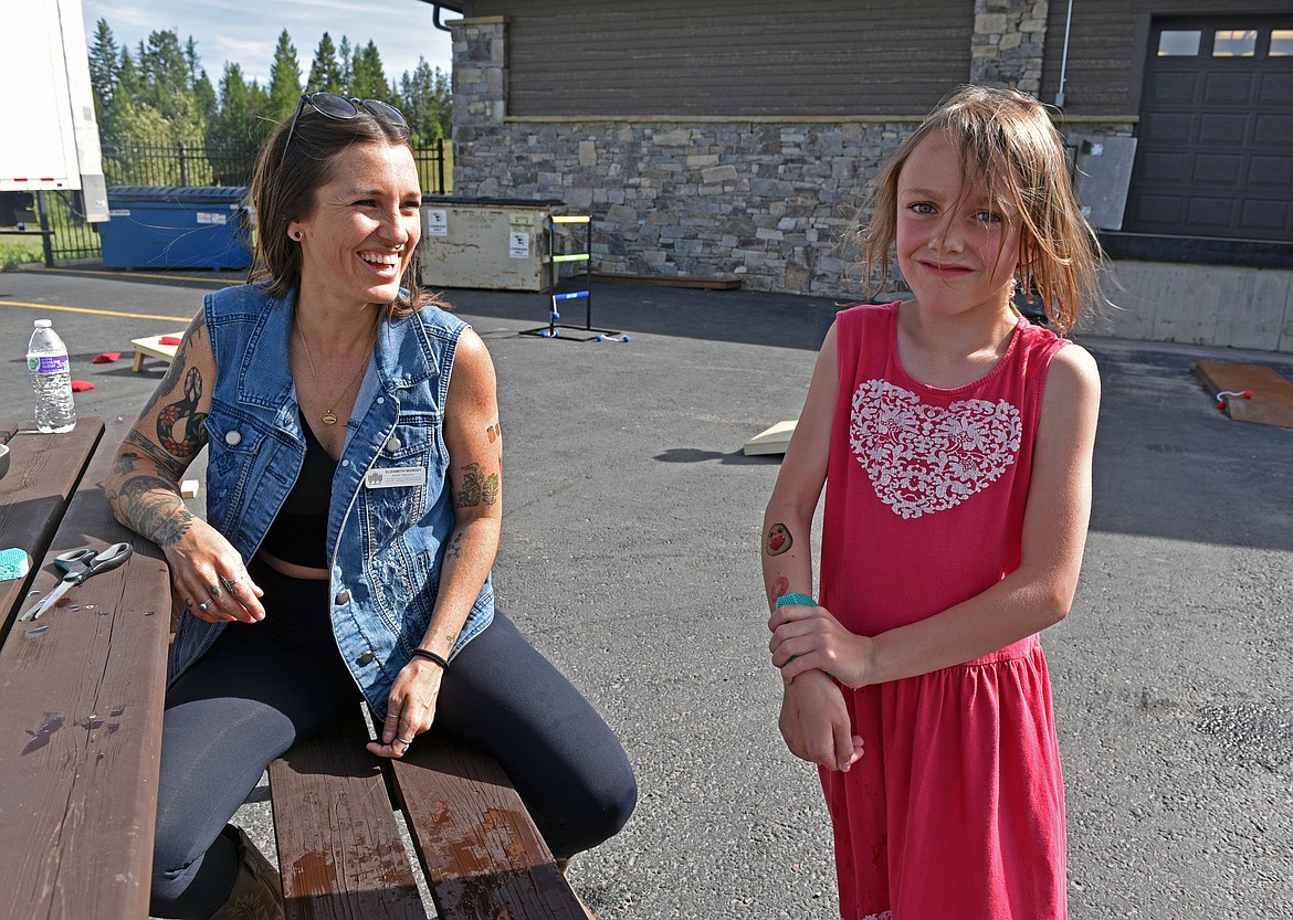 Elizabeth Munsey helps apply fruit and veggie temporary tattoos at the NVFB Forever June celebration. (Kelsey Evans/Whitefish Pilot)