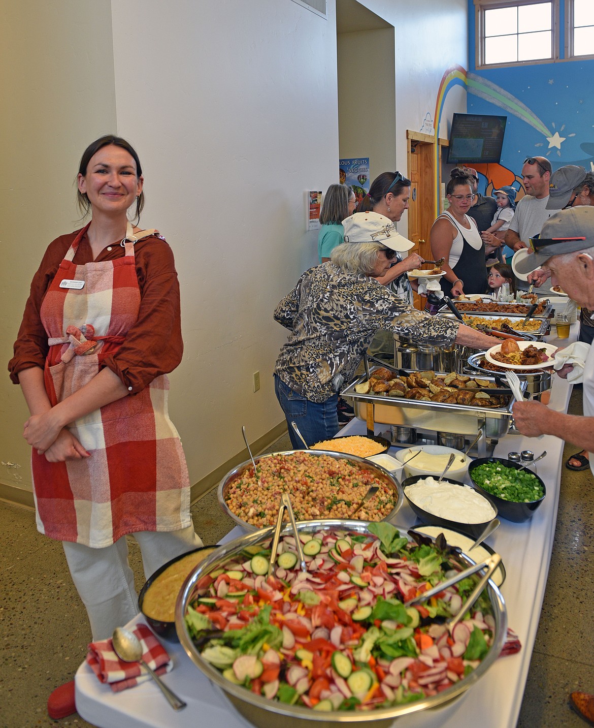 Savannah Lust smiles with a rainbow of fresh food at the NVFB Forever June community BBQ last Friday. (Kelsey Evans/Whitefish Pilot)