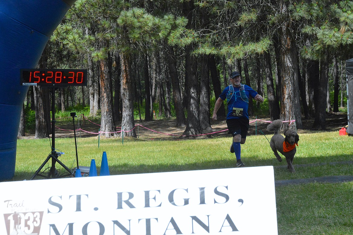 Morris Hill, from St. Regis crosses the finish line a the Community Park Saturday afternoon with his running buddy Barnabas. The two started at Ward Creek and helped complete the MadRad Team 2's 50 Mile Relay. (Mineral Independent/Amy Quinlivan)