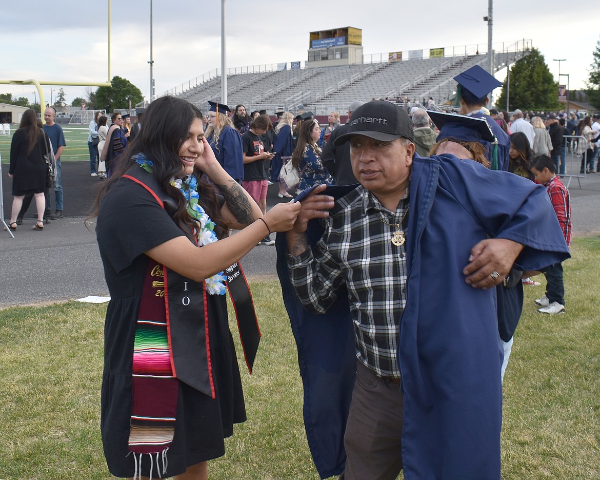 Marielly Reyes, left, puts her graduation gown on her father Jacob Reyes for a photo after the ceremony Friday.