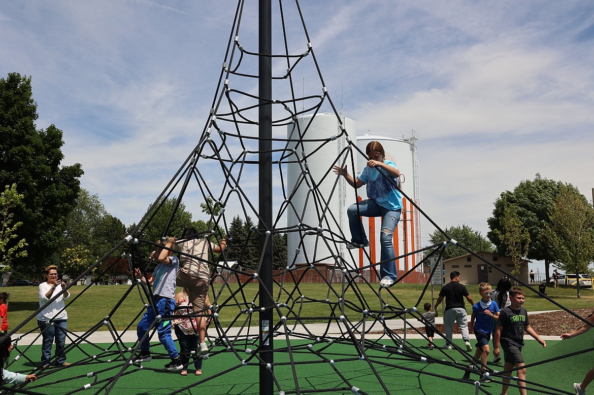 Children climb the ropes during the grand opening of the new playground.