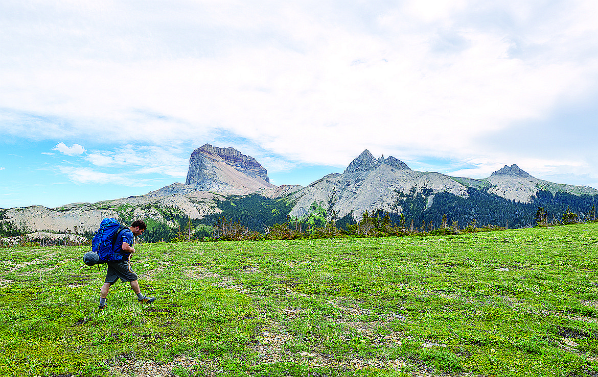 A hiker heads up Lee Ridge with with Chief Mountain in the background in Glacier National Park.