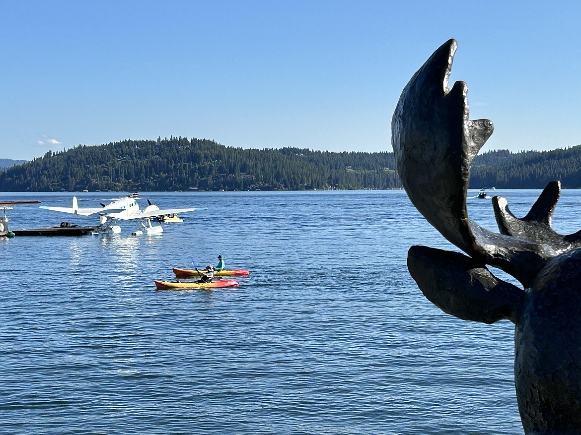 Kayakers on Lake Coeur d'Alene cruise past the Mudgy Moose statue at Independence Point on Wednesday.