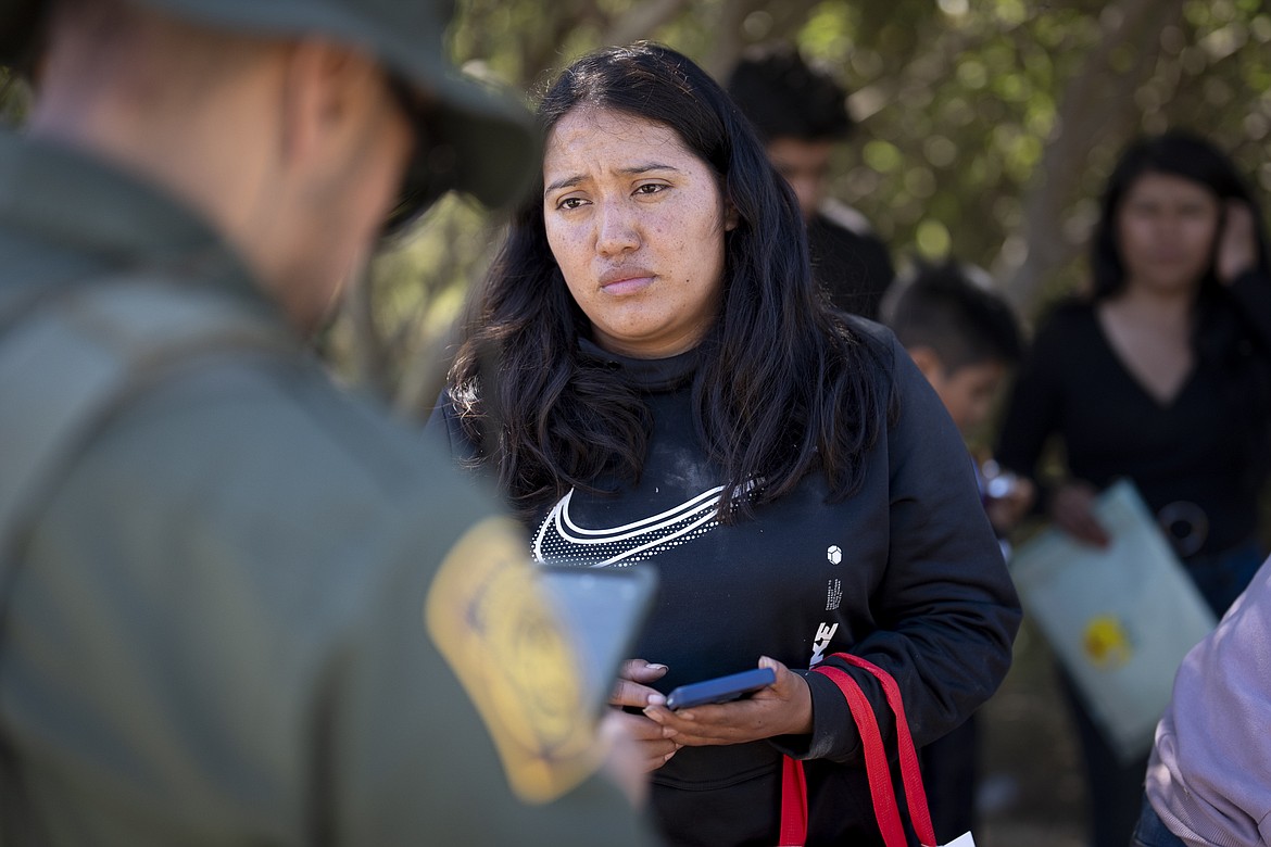 A migrant woman from Mexico talks with a Border Patrol agent before being transported in a van to be processed for asylum, Wednesday, June 5, 2024, near Dulzura, Calif. (AP Photo/Gregory Bull)