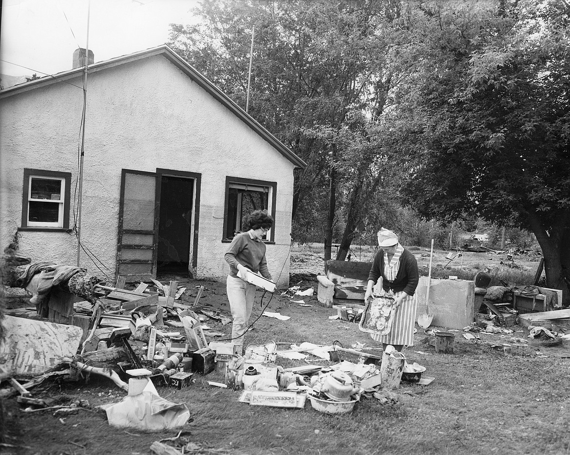 Mrs. Fred Christman and high school senior Karalee sort through soaked belongings at their home near the Red Bridge in Columbia Falls in June 1964. The family lived there for 27 years. (Mel Ruder/Hungry Horse News)