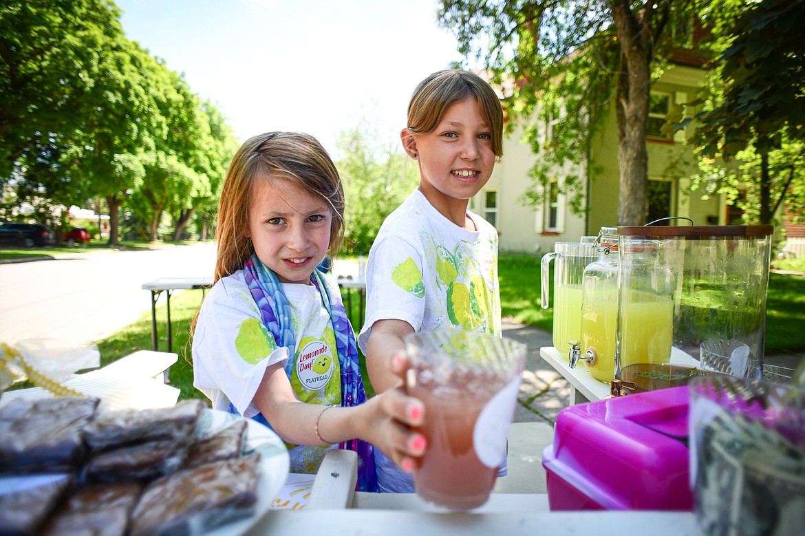 Lucy and Parker Waldenberg serve a cup of their Cherry Basil Lemonade at their 2 Sisters' Lemonade stand along Fifth Avenue East as part of the Lemonade Day program on Saturday, June 22. (Casey Kreider/Daily Inter Lake)