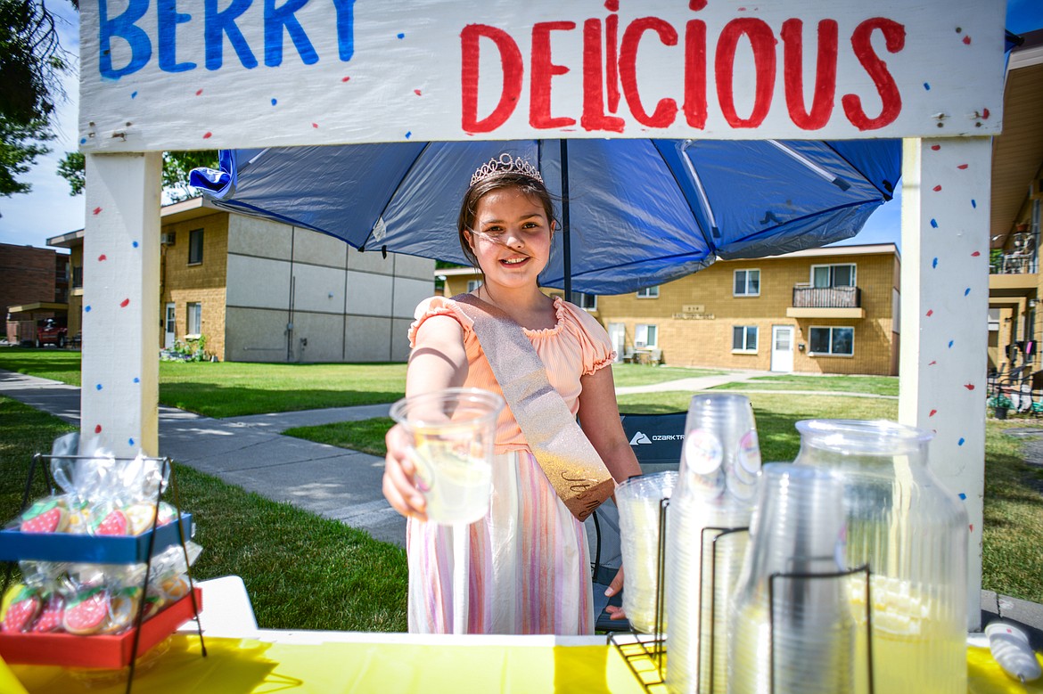 Faithlyn Hall serves a cup of lemonade at her Berry Delicious stand along Third Avenue West as part of the Lemonade Day program on Saturday, June 22. (Casey Kreider/Daily Inter Lake)