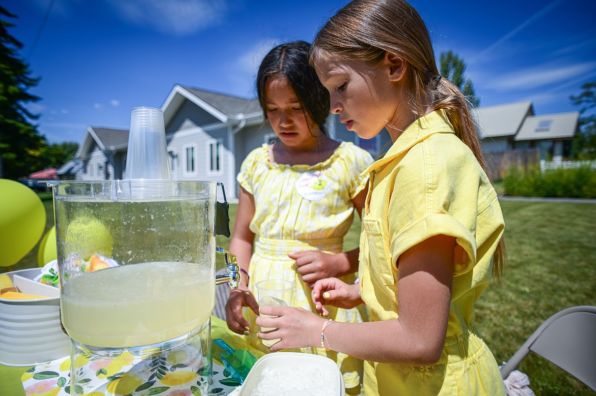 Gwen Welder and Mara Russell pour a cup of lemonade at their Maralade Honey Squeezed lemonade stand along Sixth Avenue West as part of the Lemonade Day program on Saturday, June 22. (Casey Kreider/Daily Inter Lake)