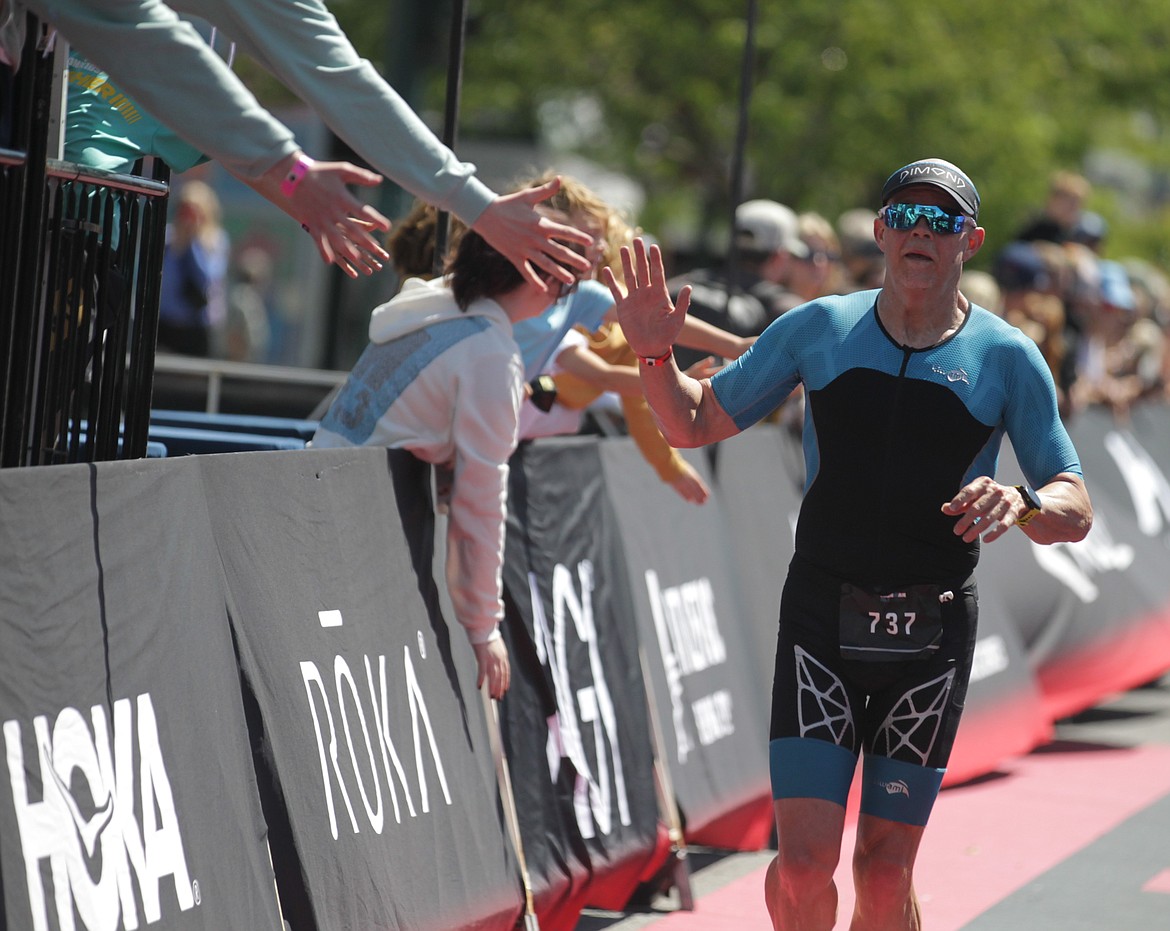 JASON ELLIOTT/Press
Coeur d'Alene's Kip Taylor, 53, celebrates with a few members of the crowd before crossing the finish line of Sunday's Ironman 70.3 Coeur d'Alene.