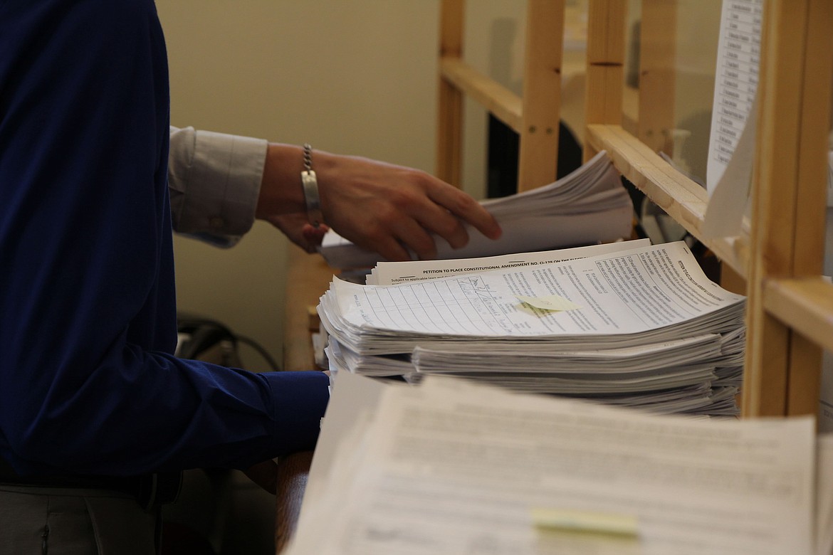 Lewis and Clark County election workers in Helena sort stacks of signature petition forms for CI-128 on June 20, 2024. (Mara Silvers/Montana Free Press)