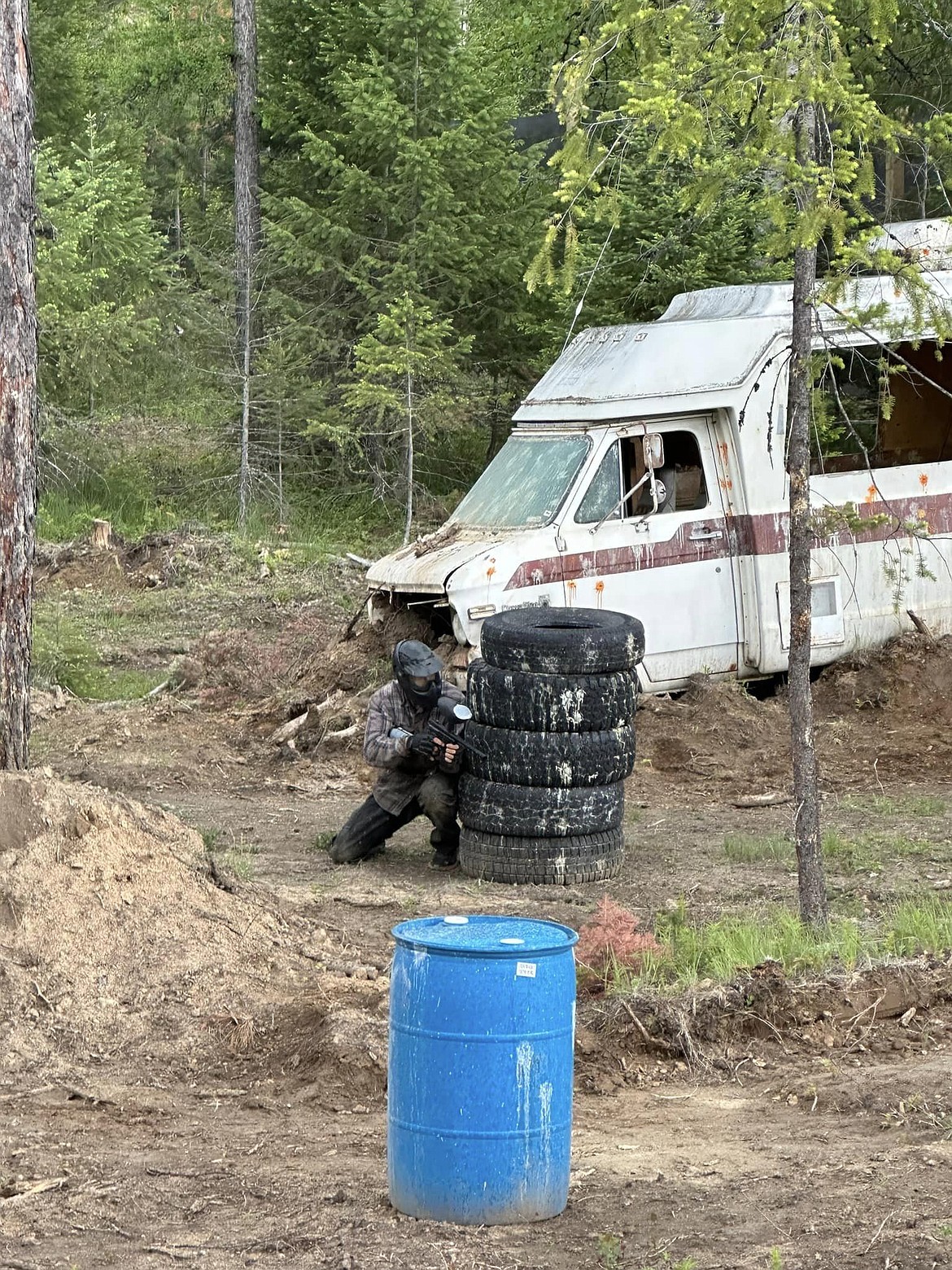 A participant at 7B Paintball attempts to hide behind a stack of tires in an attempt to avoid during hit during a recent paintball event at the Sagle area course.