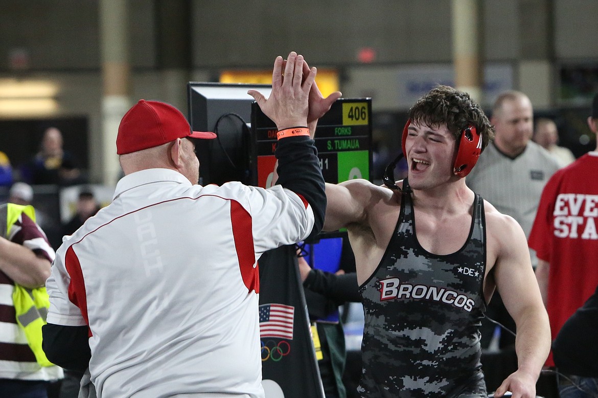 Lind-Ritzville/Sprague wrestling Head Coach Jason Hilzer, left, high-fives senior Gabe Smith after Smith won the 2B 195-pound weight class at the 2024 Mat Classic in Tacoma in February.