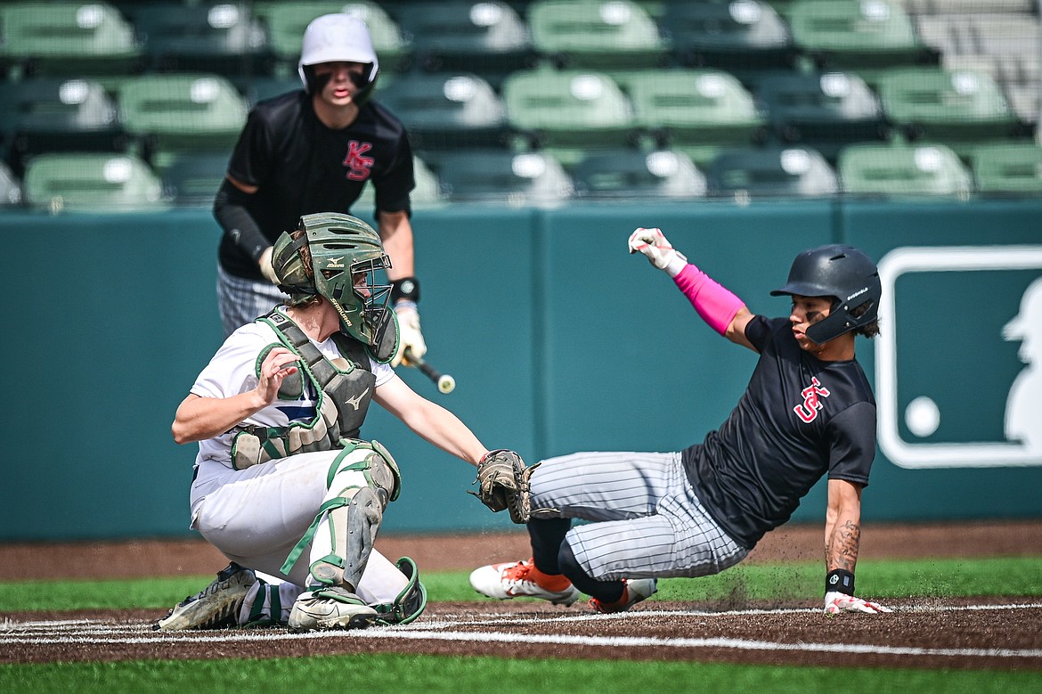 Kalispell Sluggers' Jordan Griffin (0) slides around the tag at home plate by Badrock catcher Will Sisson (4) during the Badrock Invitational at Glacier Bank Park on Saturday, June 29. (Casey Kreider/Daily Inter Lake)