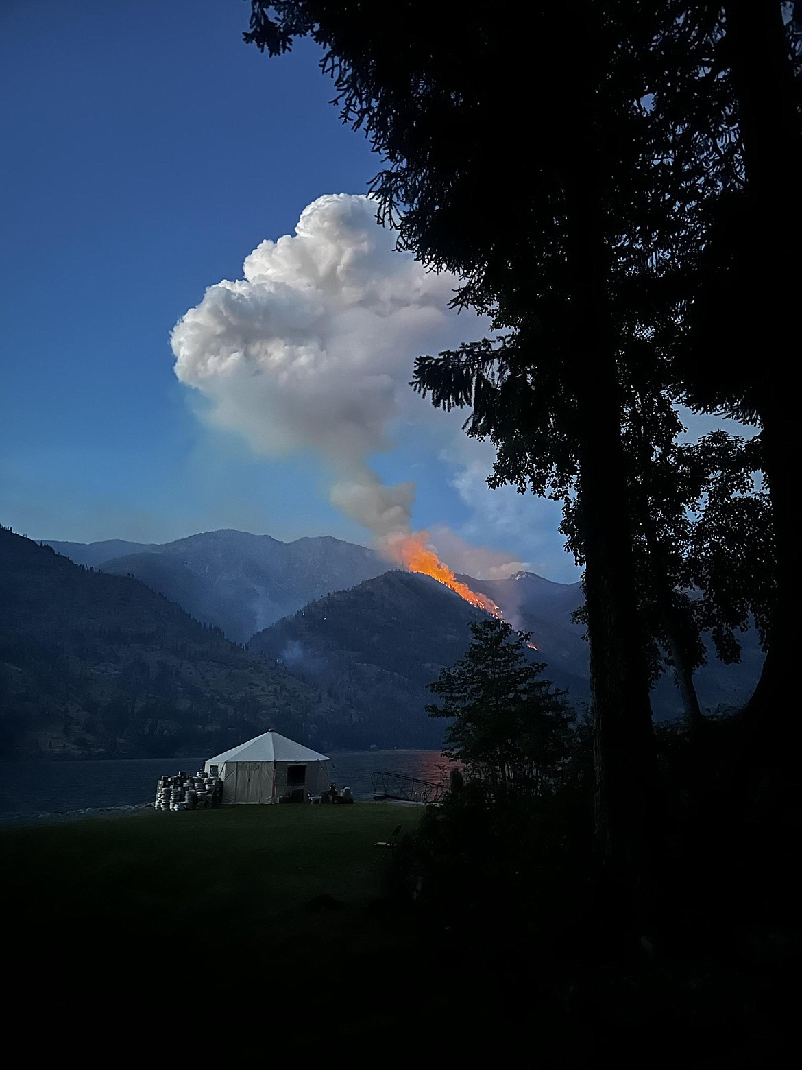 Flames from the Pioneer fire clearly visible coming from a mountaintop near Lake Chelan. The fire is in rough terrain making it difficult to fight.