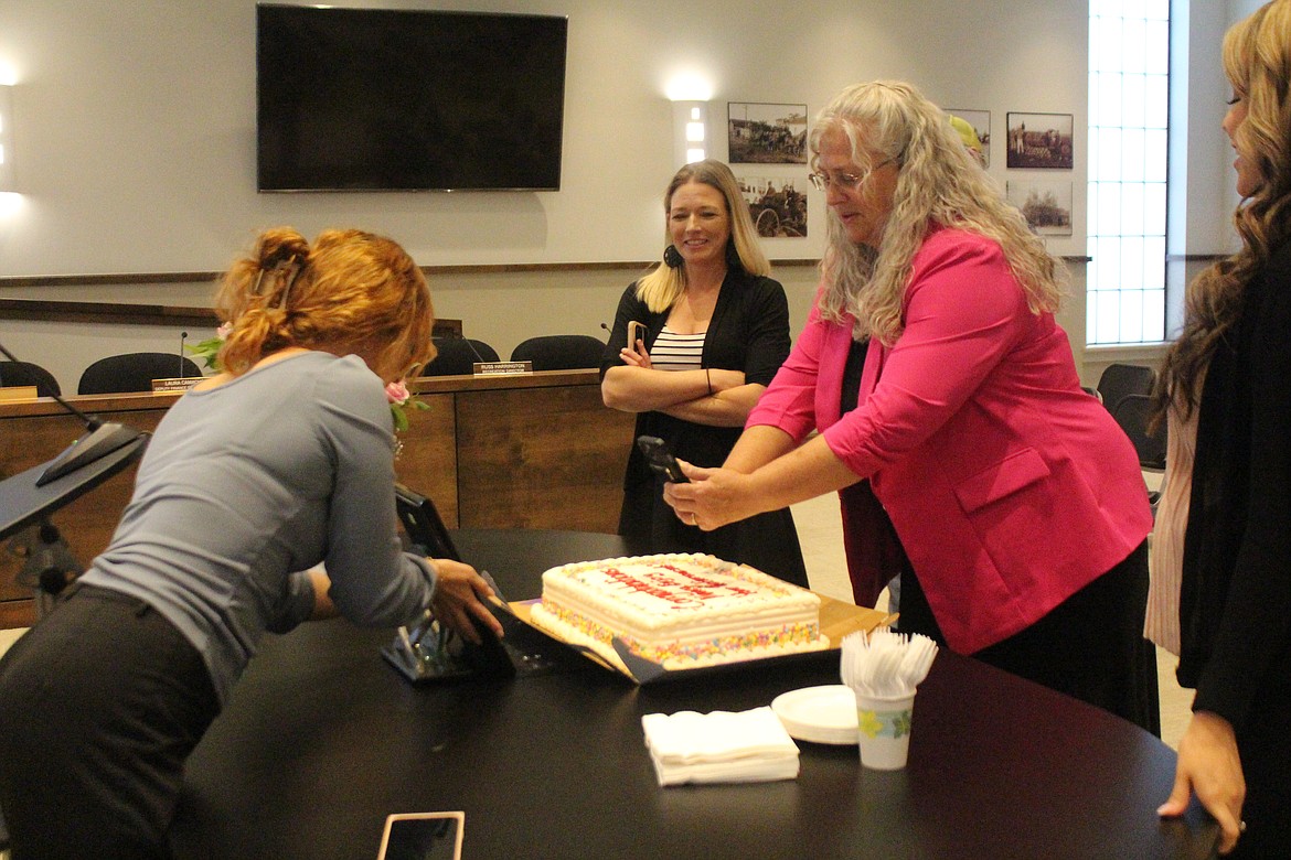 Quincy City Clerk-Finance Director Nancy Schanze, right, snaps a picture of her retirement cake and an appreciation plaque, surrounded by her staff.