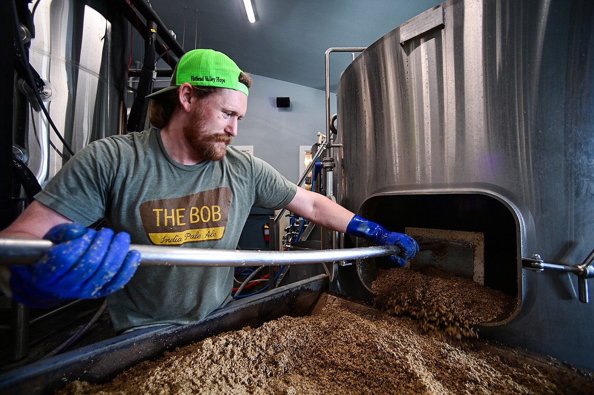 Sacred Waters Brewing Company brewer Marty Vollmer sweeps spent grain into a bin, which the company then donates to a local farmer for use on Wednesday, July 3. (Casey Kreider/Daily Inter Lake)