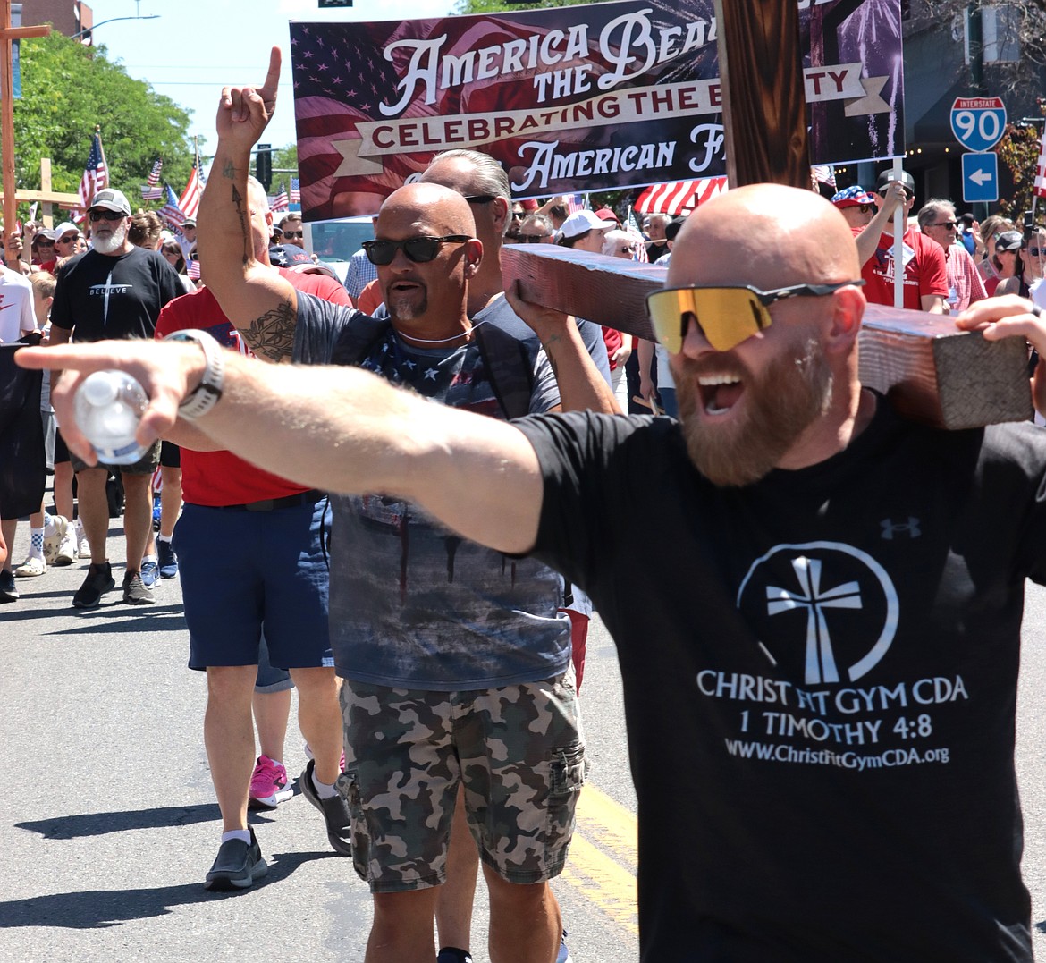 Robbie Walden points as he carries a cross with Jonathon Owens in the Fourth of July parade in Coeur d'Alene.