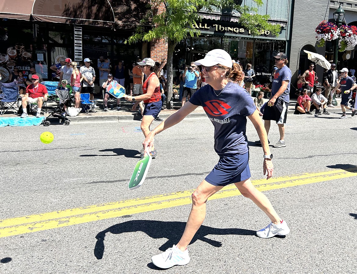 Bridget Lee plays pickleball as she makes her way on the parade route.