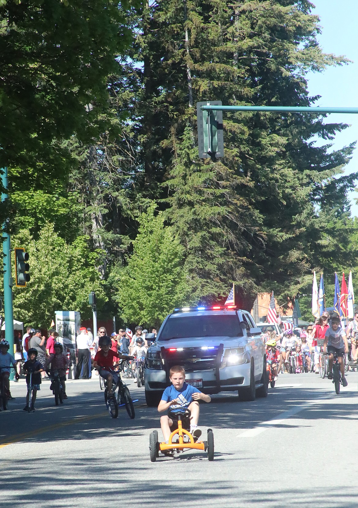 A youngster charges ahead of a Sandpoint Police officer leading the children's parade. The event kicked off the Sandpoint Lions Fourth of July fun in downtown Sandpoint. The pair of parades packed the downtown as the more-than-hour-long Grand Parade and the shorter children's parade saw thousands of people pack the downtown core.