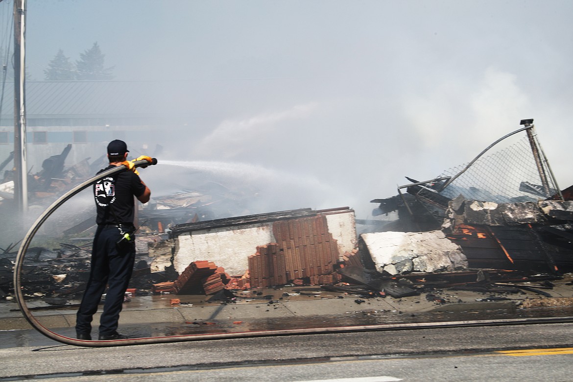 A Sandpoint firefighter aims water at a spurt of flame as crews worked to completely extinguish a fire which destroyed the Army Surplus building in downtown Sandpoint.