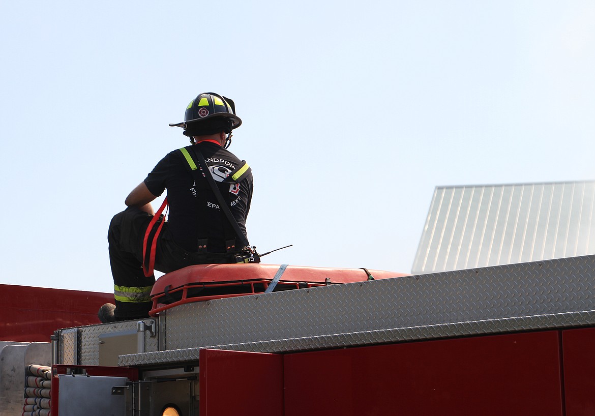 A Sandpoint Fire firefighter sits atop on a fire engine Friday as he aims a stream of water at the still-smoldering fire at the Army Surplus building in downtown Sandpoint. The fire was reported about 10:15 p.m. on July 4.