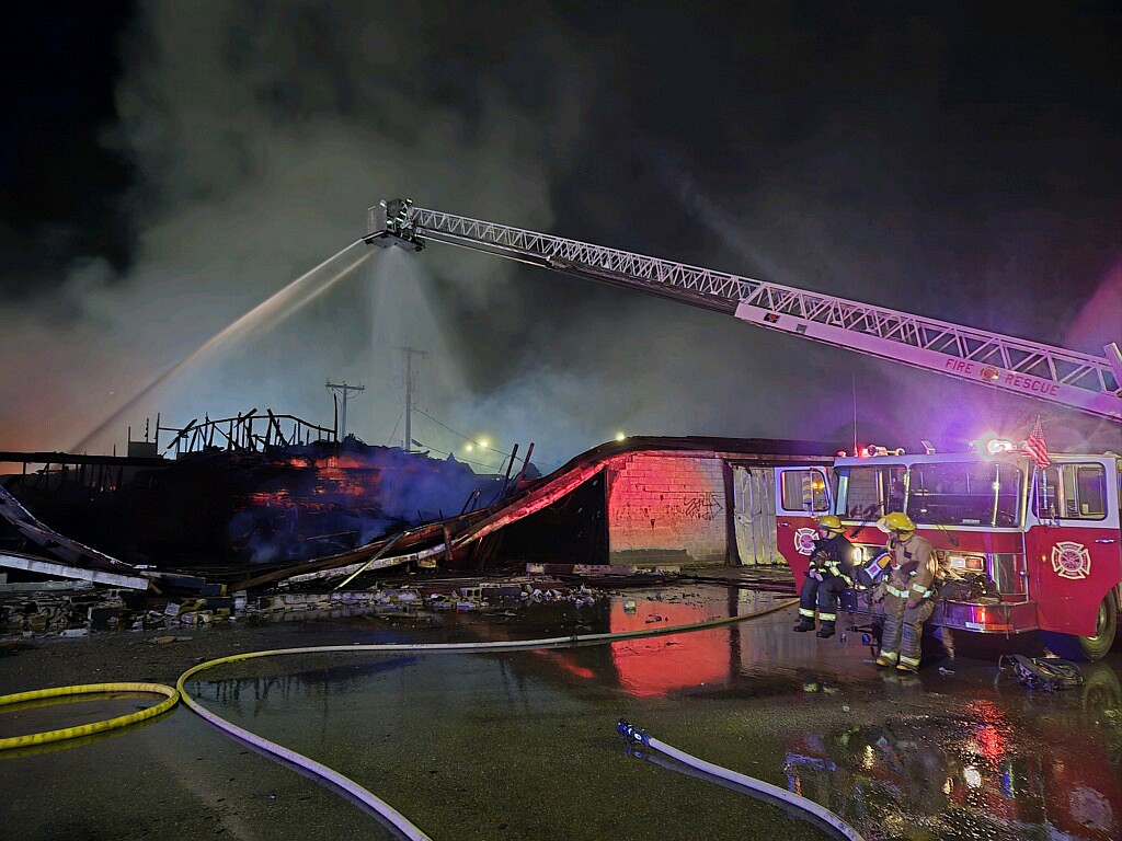 Area firefighters aim water at the Army Surplus building after the fire was engulfed in flame late July 4.