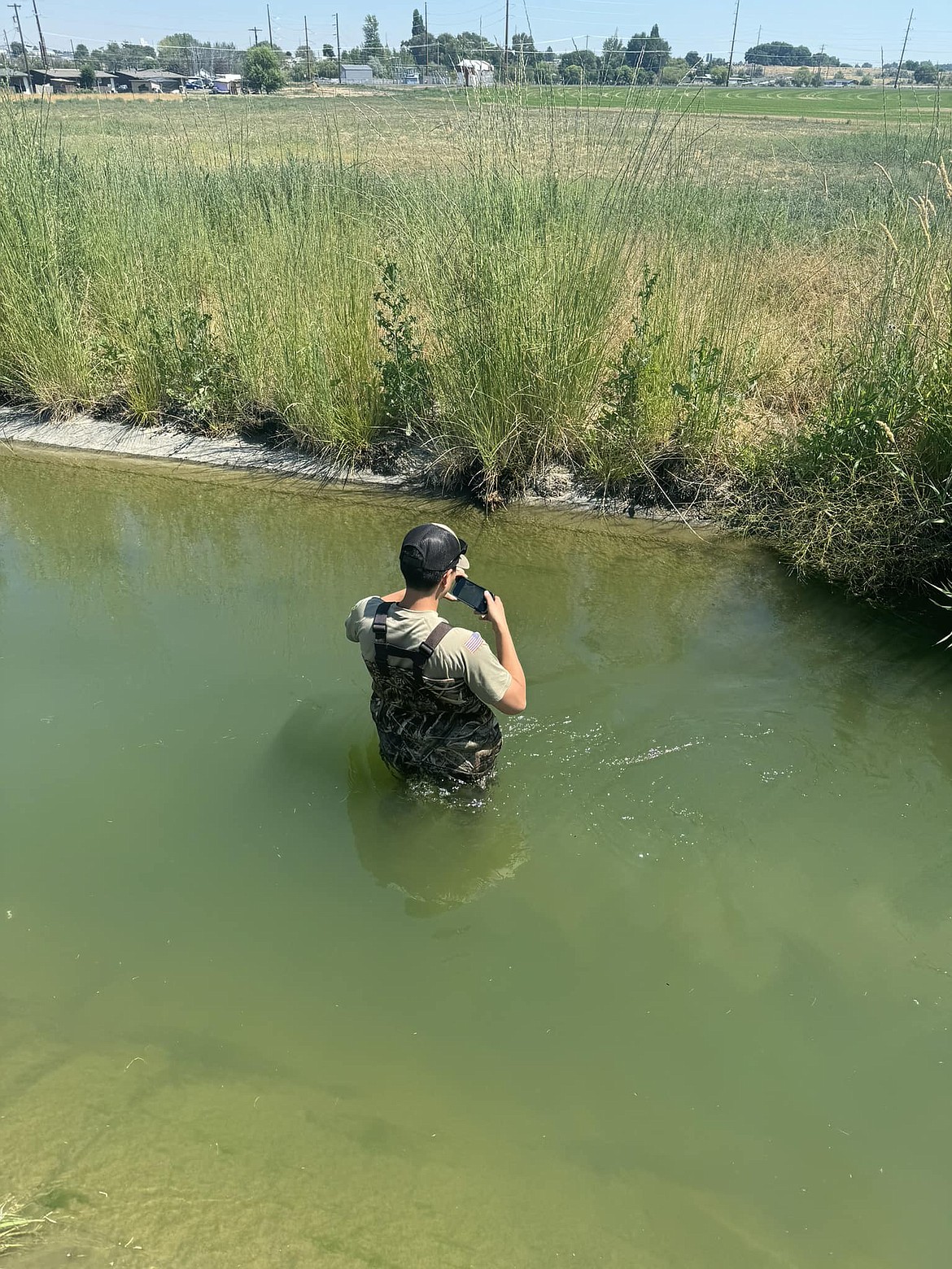 An Adams County Sheriff’s deputy wades through an irrigation canal while searching for evidence in a shooting July 4 near Othello. Adams County Sheriff Dale Wagner said it is important that people do not wade or swim in the canals, as they can be very dangerous. Deputies only entered the water out of necessity in this instance due to the need to gather evidence.