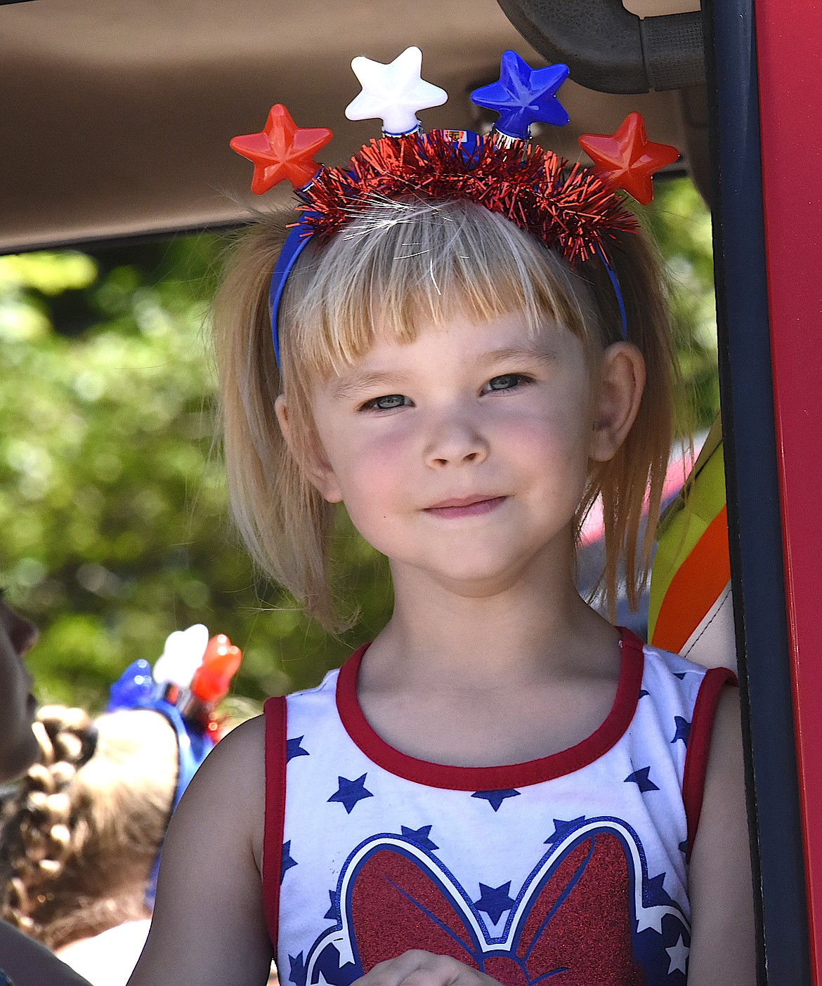 Little Miss Fourth of July looks out the window of a fire engine as the Charlo Fourth of July Parade slides down Highway 212. (Berl Tiskus/Leader)