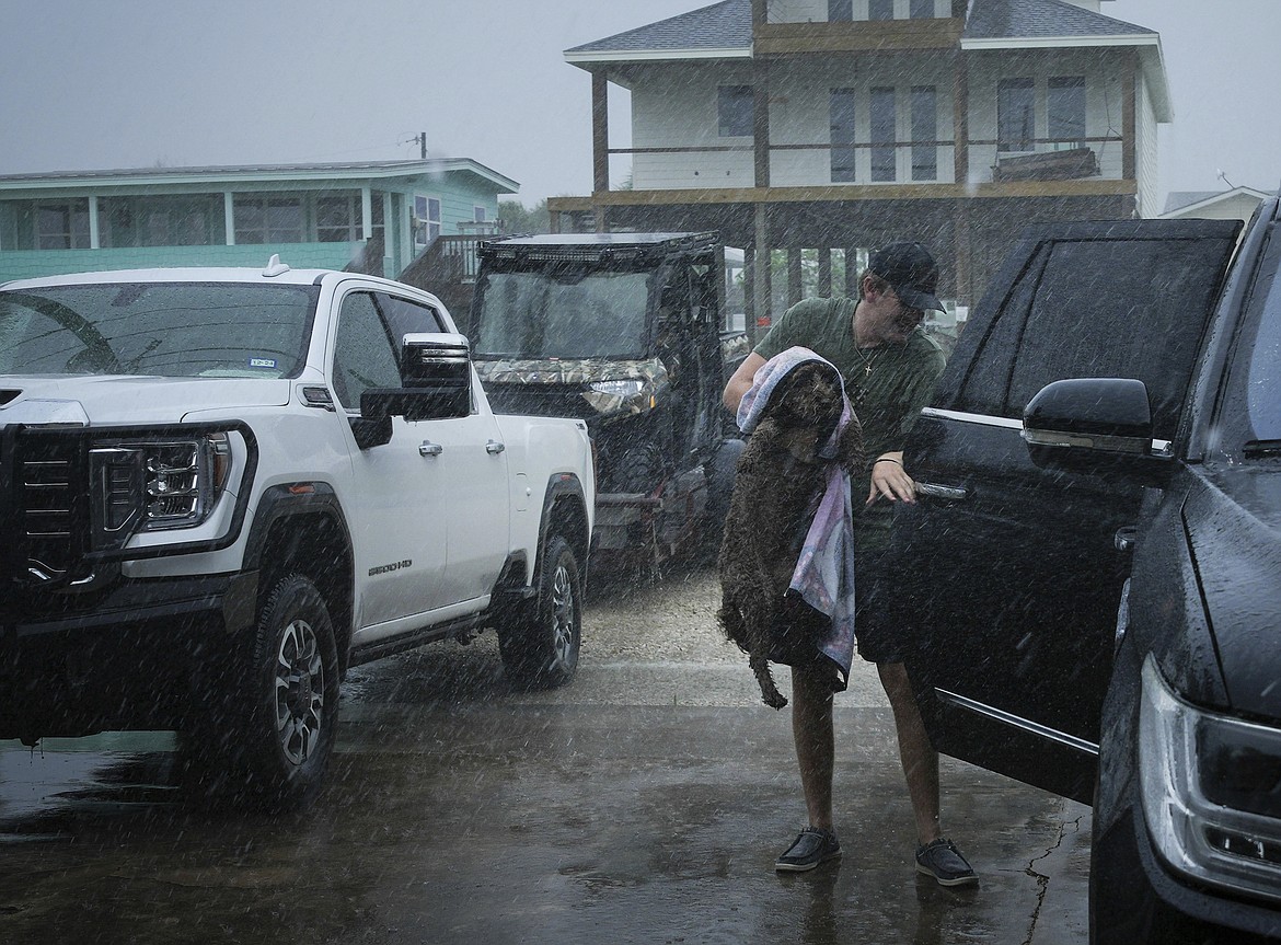 Blake Braun loads his dog Dolly into his family's vehicle as outer bands from Tropical Storm Beryl begin to hit the coast Sunday, July 7, 2024, in Port O'Connor, Texas. (Jon Shapley/Houston Chronicle via AP)