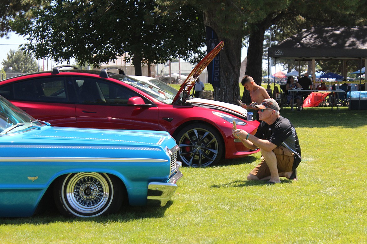 Car enthusiasts look at, and snap a few photos of, the entries in the July 4 car show in Othello.