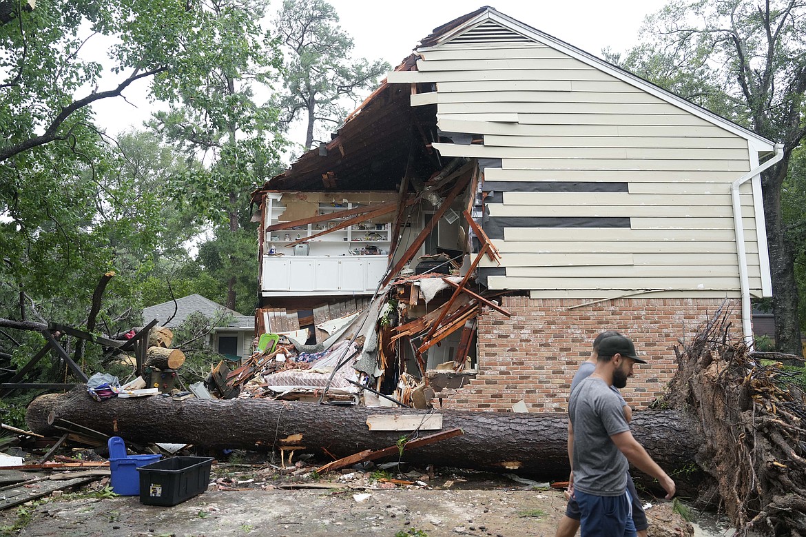 People gather outside a home in the 17400 block of Rustic Canyon Trail where Maria Loredo, 74, died after a tree fell on her second story bedroom during Hurricane Beryl Monday, July 8, 2024, in Houston. (Melissa Phillip/Houston Chronicle via AP)