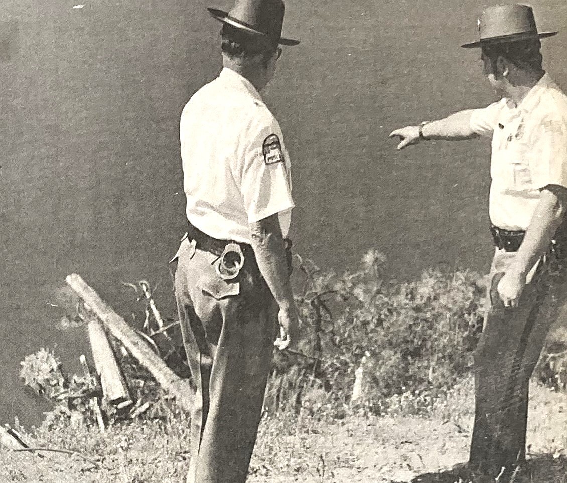 Sgt. Jim Guy, right, and Police Chief Del Larson look at the spot in Spokane River where a triple killer was shot and captured.