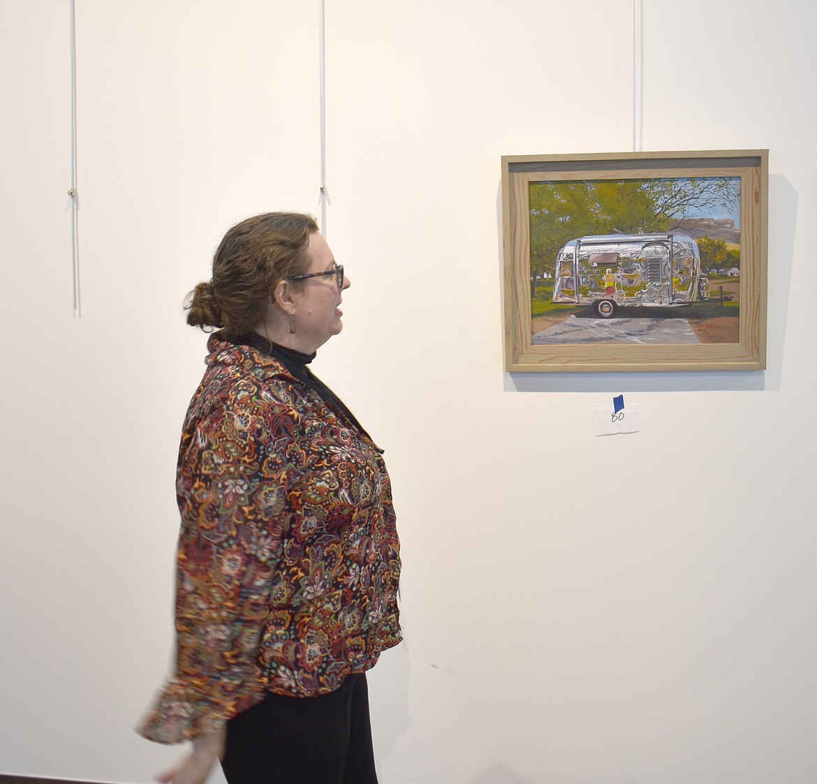 Moses Lake Museum & Art Center Director Dollie Boyd shows her favorite painting in Deon Matzen’s “Vanishing Rural America” exhibit, a self-portrait the artist did of her reflection in the side of a Silver Streak Trailer.