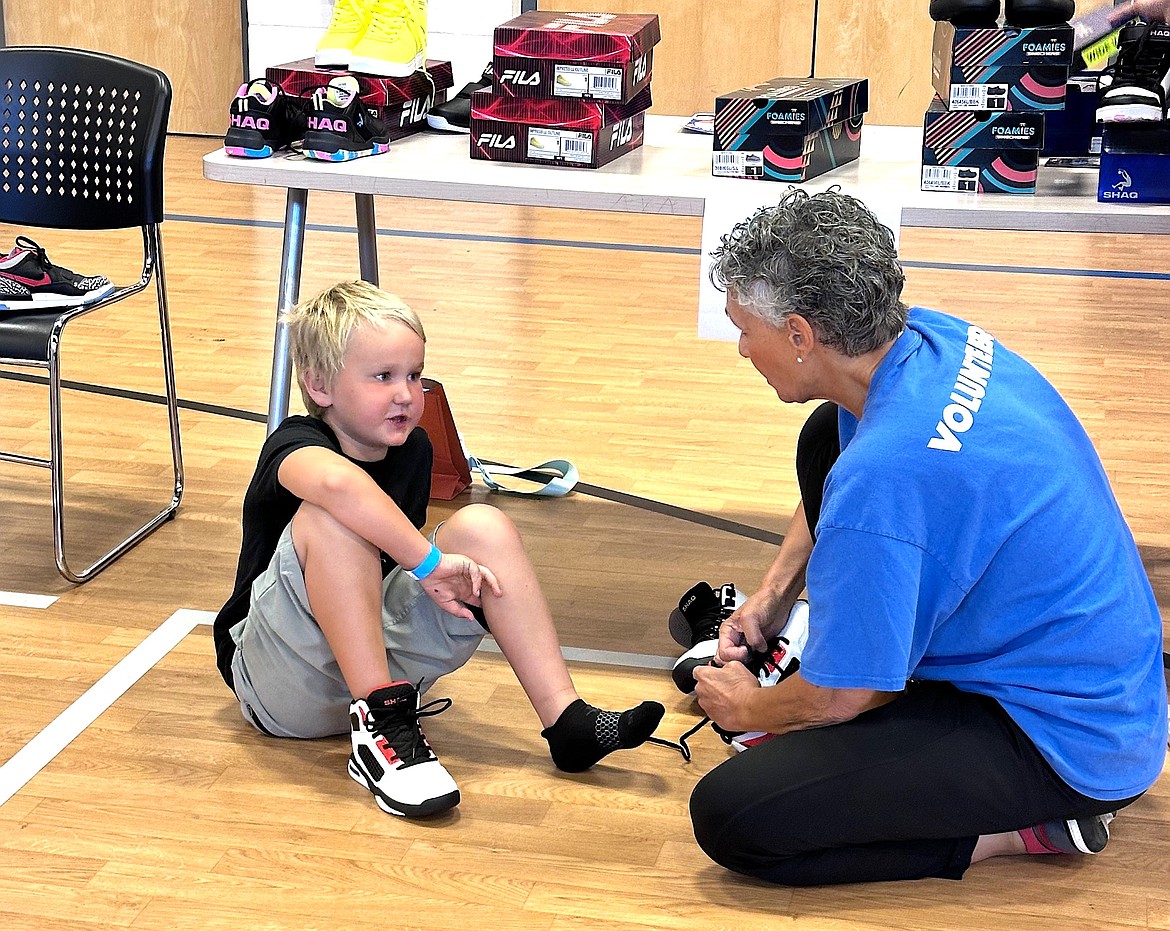 A volunteer helps a boy try on new shoes at the Lola and Duane Hagadone Boys and Girls Club of Kootenai County on Wednesday.