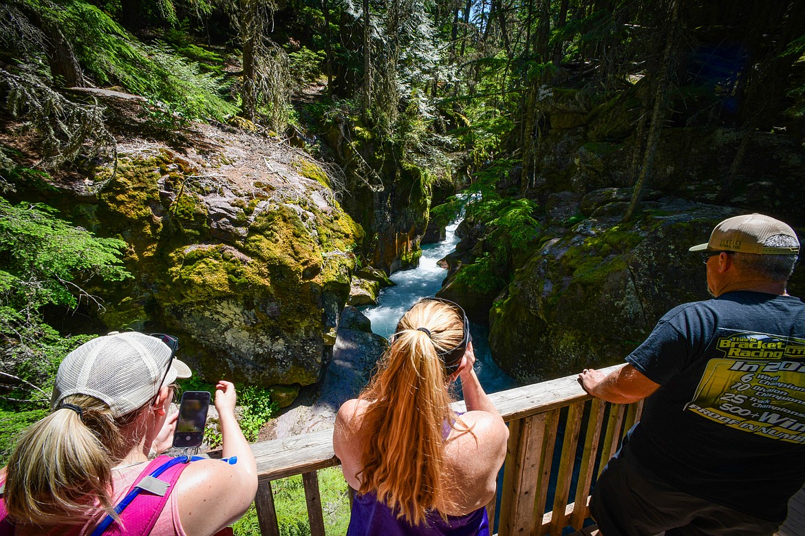 Visitors take photographs of the gorge from the footbridge over Avalanche Creek at the start of the Avalanche Lake trail in Glacier National Park on Thursday, July 11. (Casey Kreider/Daily Inter Lake)