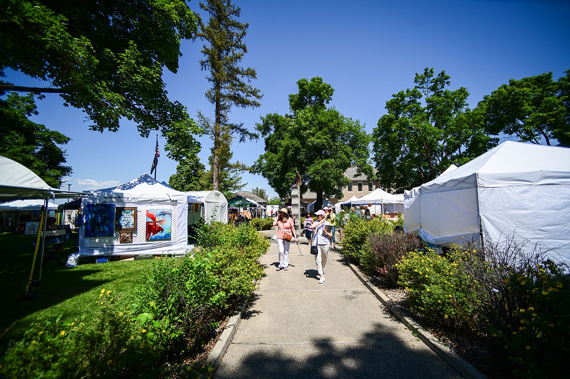 Two visitors walk through the Hockaday Museum's Arts in the Park at Depot Park in Kalispell on Friday, July 12. The event features over 80 art and craft booths, food trucks, a wine and beer garden, over 40 musical performers and community partner booths with free activities Friday, Saturday and Sunday July 12-14. (Casey Kreider/Daily Inter Lake)