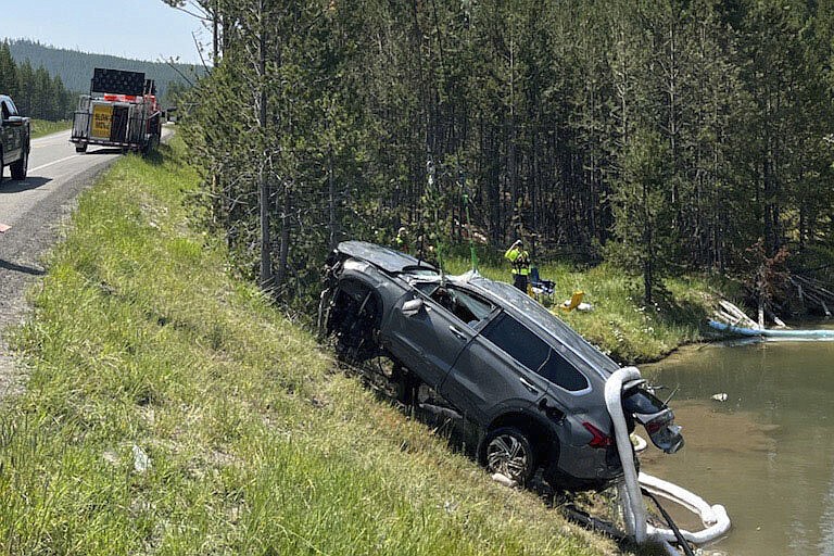 In this photo provided by the National Park Service, a sports utility vehicle is pulled from the inactive Semi-Centennial Geyser in the Wyoming area of Yellowstone National Park on Friday, July 12, 2024. The passengers were able to get out of the acidic, 105 degree Fahrenheit (41 degrees Celsius) water on their own and were taken to the hospital for treatment of non-life-threatening injuries after the crash Thursday morning, park spokesperson Morgan Warthin said in a statement. (National Park Service via AP)