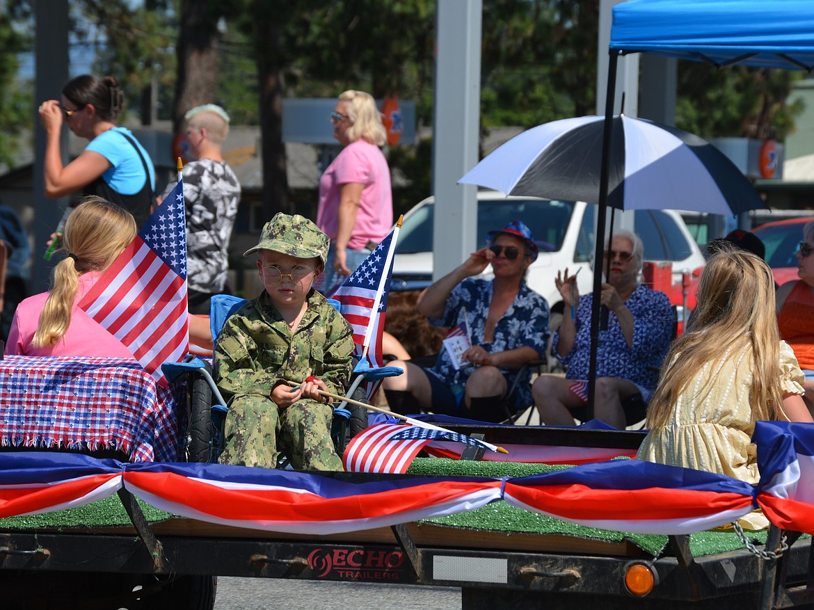 Geof and Jet Bergland watch a little boy in military fatigues be towed down Seltice Way Saturday during the Post Falls parade.