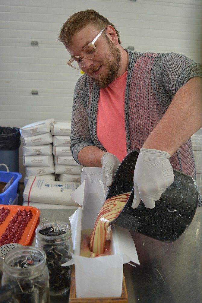 Cody Naylor, of Mountain Madness Soap Co., pours a mix of raspberries and cream soap into a mold to set before being decorated with raspberries made from glycerin.