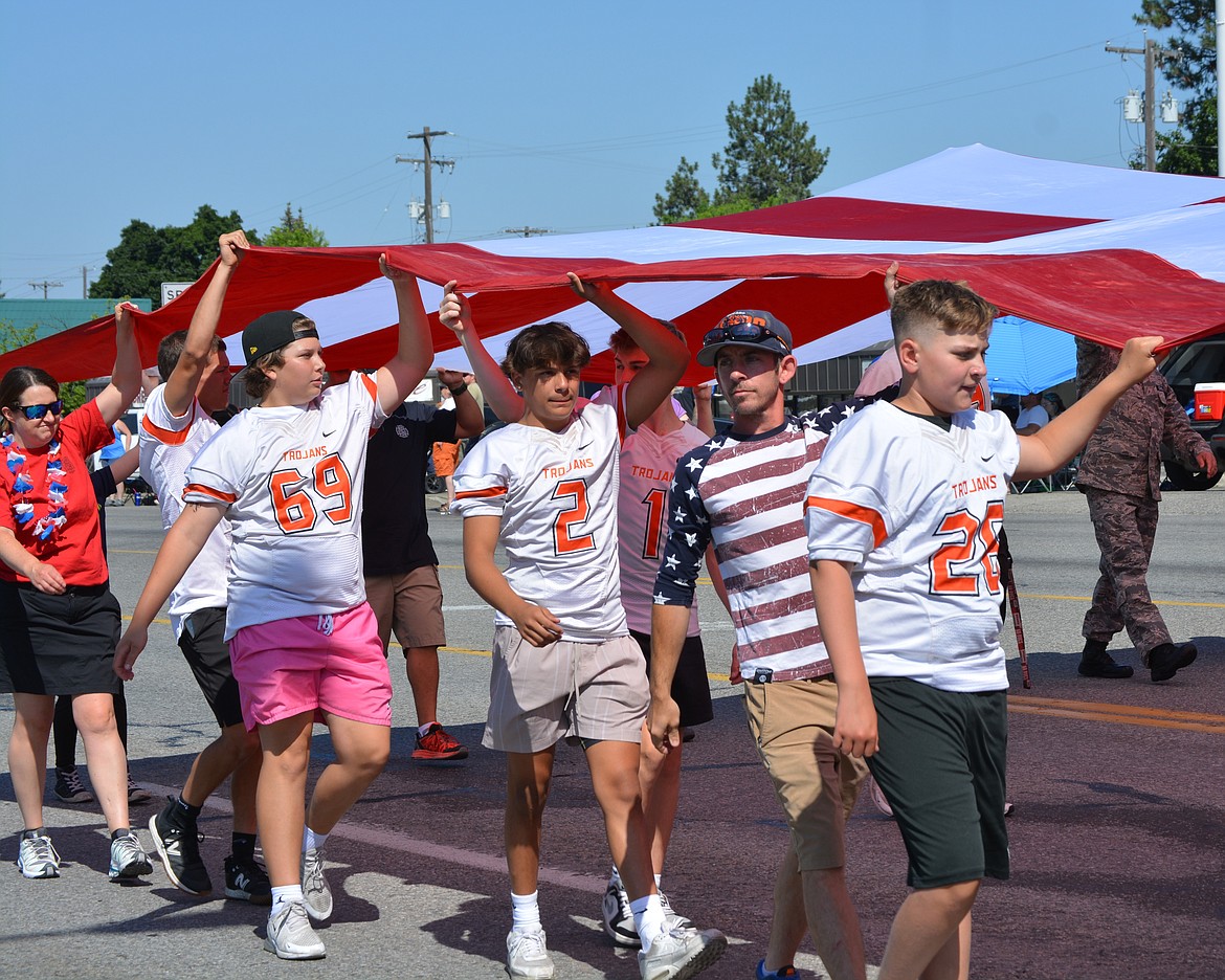 A giant flag is carried down Seltice Way by Post Falls student athletes and community members during the Post Falls parade.