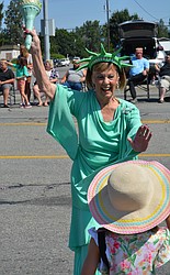 Abbi Young gets a high five from Lady Liberty as the North Idaho Sparklers pass by on Seltice Way.