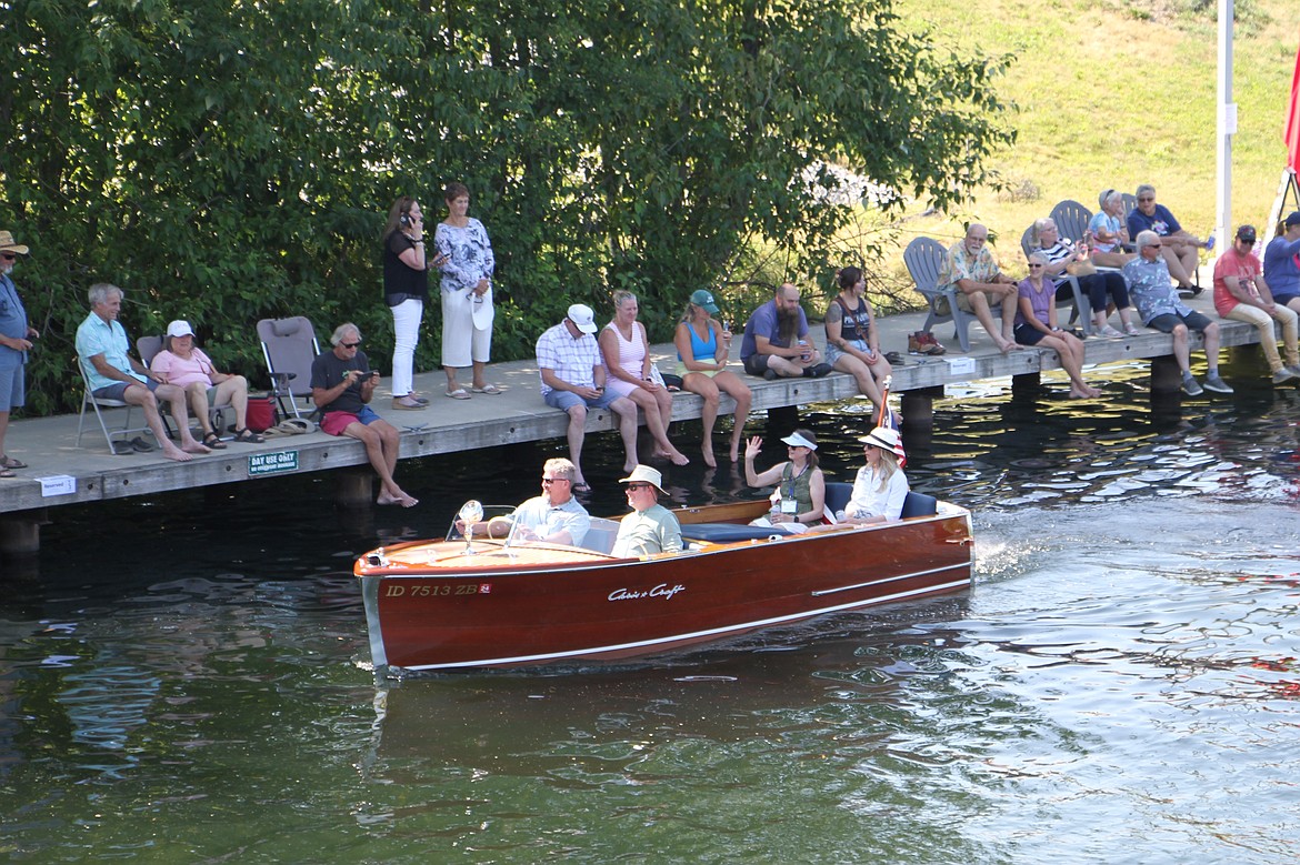 Spectators wave to a passing boat from the boardwalk by Sand Creek.