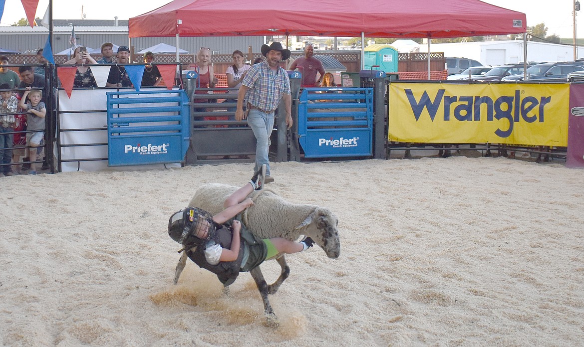 Despite a valiant effort, 5-year-old Lexi Hoskins of Ephrata tumbles off a sheep before the eight-second buzzer at the mutton bustin’ arena at Royal City’s Summerfest Friday.