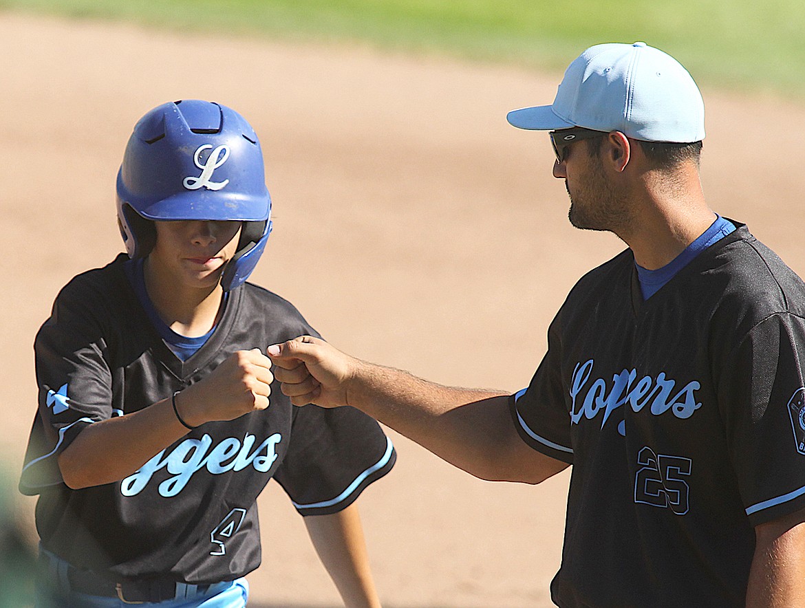 Libby American Legion baseball player Kale Riddle celebrates his RBI single with first base coach Ryan Stapley in the bottom of the second inning with two outs. The Loggers beat the Flathead As 11-7 in nine innings. (Paul Sievers/The Western News)