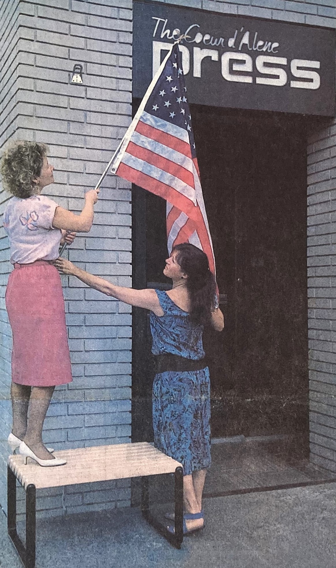 Coeur d’Alene Press employees Laura Stach, left, and Suzanne Richards proudly hoist the American flag.