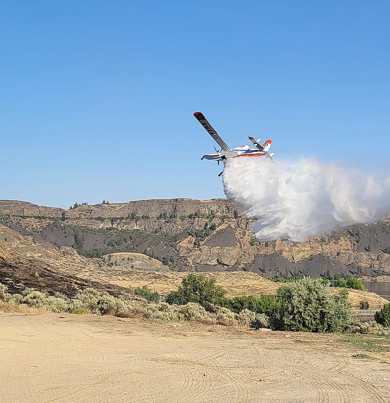 An aircraft drops water on  the Sunbanks Fire Tuesday. The blaze, which burned 100 acres in Electric City, was mostly out Wednesday.