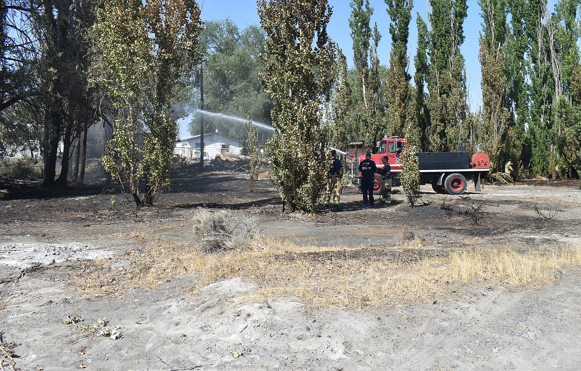 A Moses Lake Fire Department crew waters down the scene of a fire that broke out during Wednesday evening’s wind storm.