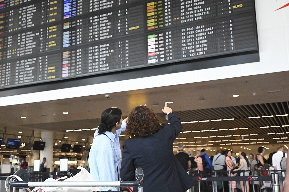 Travelers wait for information in front of a departure board at Brussels International Airport in Brussels, Friday, July 19, 2024. A global technology outage grounded flights, knocked banks and hospital systems offline and media outlets off air on Friday in a massive disruption that affected companies and services around the world and highlighted dependence on software from a handful of providers. (AP Photo/Harry Nakos)